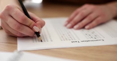 Bayan öğrenci üniversitede sınav kağıdında doğru cevabı vurguluyor. Kadın, geçmiş akademik yıldaki bilgileri yavaş çekimde kontrol ediyor