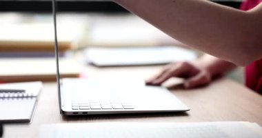 Kadın yönetici, rapor yazmaya devam etmek için modern dizüstü bilgisayarı açar. Kadın elektronik cihaz üzerinde çalışmaya hazır. Ofiste ağır çekimde oturuyor.