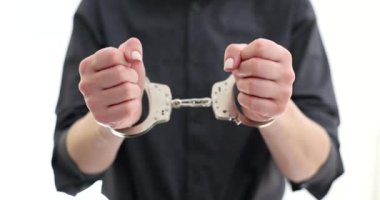 Elleri kelepçeli bir kadın beyaz arka planda el kaldırıyor. Gri gömlekli kadın iş yerinde yolsuzluktan tutuklandı