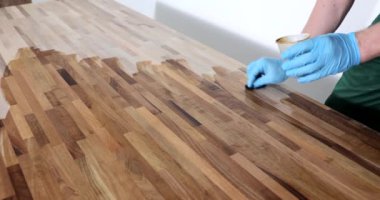 Lastik eldivenli ustabaşı, pürüzsüz ve parlak yüzey için parke işliyor. Adam ahşabı cilalıyor yavaş çekimde yenilemeye hazırlanıyor.