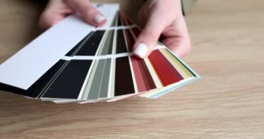 Kadının elleri ahşap masanın üstündeki renk paletinden yelpaze yapıyor. Tasarımcı, iç tasarım yavaş çekim için duvar kağıtlarının renk çeşitlerini sunar