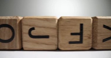 İngiliz harfli tahta bloklar beyaz masa yüzeyinde rastgele uzun sıra diziliyor. Çocukların eğitimi ve gelişimi için tasarlanmış odundan yapılmış küpler.