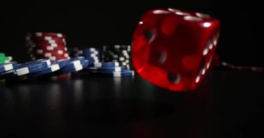 Adam siyah masa yüzeyine renkli poker fişleri yakınlarında kırmızı zarlar atıyor. Siyah arka planda profesyonel kumar oynamak için ekipman