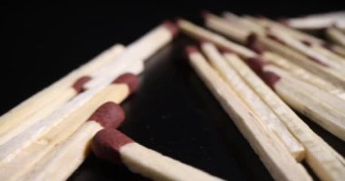 Koyu masa yüzeyine saçılmış kahverengi sülfür başlarıyla eşleşiyor. Siyah arka plan makrosu üzerinde ateş çıkartmak için yanıcı tahta kibrit çöpleri