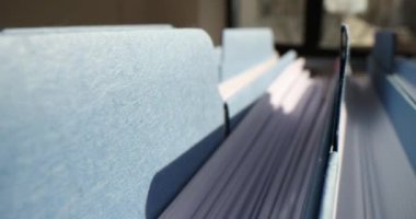 Ofis çekmecesindeki sıra sıra dizilmiş proje materyalleri ve verileri içeren mavi klasörler. Analiz ve araştırma için kaydedilen bilgilere sahip dosyaları arşivle