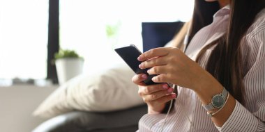 Kadın el evde kanepe hakkında maliyetlerini kullanarak smartphone tutar. Mali reklam özgürlüğünü düzey havale yüklenici kavramı için iç bilgi doğrular