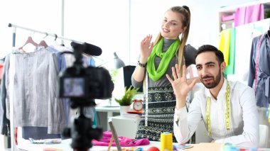 Çift karı koca portre dalga el ve kamera bakar, takipçisi selamlıyorum ve abonelik seviyor söylüyorlar. Dikiş ve onarım bez konseptinde aile şirketi.