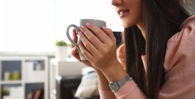 Hintli kadın kupa elini gülümsüyor tutar ve kanepede yatıyor. Evde eğitim kavramı çalışma.