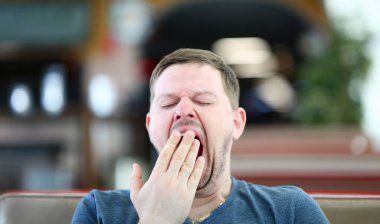 Genç çekici adam el ile ağız kapsayan kafede esniyor. İşleme aşırı çalışma kavramı nedeniyle uyku kronik eksikliği sendromu.