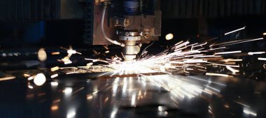 Metalurjik bitki arka planında metal işleme lazer metali için makineden çıkan kıvılcımlar. Otomotiv üretim kavramı için tamamlanmış parçalar üretiliyor
