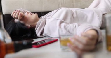 Drunk woman with glass of alcohol lies on floor. Loneliness and female alcoholism concept
