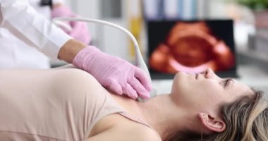 Doctor examines neck of female patient with ultrasound machine during medical examination in modern hospital. Healthcare thyroid diagnosis and medical concept.