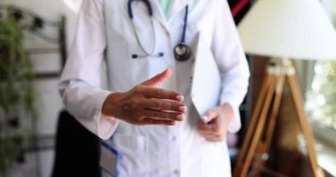 Kadın doktor el sıkışmak ya da selamlaşmak için elini uzatıyor. Doktor sigortasını öğrenmek ve tıbbi bakım sağlamak.