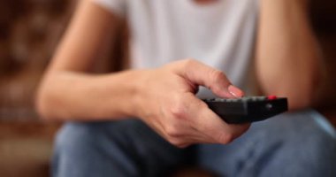 Uzaktan kumandalı bir kadın evde televizyon izliyor. TV kanallarının pasif görüntüsü