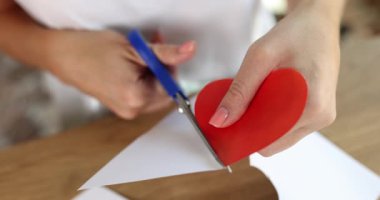 Kadın elleri kağıttan kırmızı kalbi kesmiş. Sevgililer Günü ve Anneler Günü için hediye konsepti