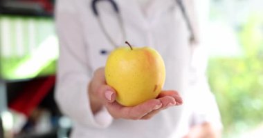 Doktor beslenme uzmanının elinde sarı elma var. Apple çeşitliliği sağlık yardımları ve kalori kavramı