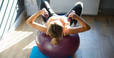 Spor salonundaki halterlerle çalışan bir kadının en iyi görüntüsü. Genç bir kadın dambıllarla spor yapıyor. Sağlıklı yaşam tarzı kavramı