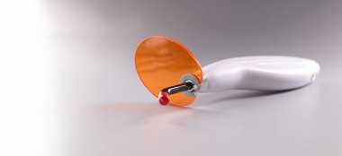 Close-up of polymerizer, electrical tool with orange protective. Dentist professional tool for tooth whitening or cleanse treatment. Stomatology, dentistry concept