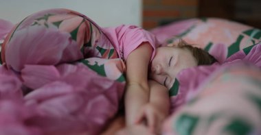 Yatakta tatlı tatlı uyuyan küçük bir kızın portresi. Gündüz uykusu. Aktif günden sonra küçük bir çocuk dinleniyor. Sağlıklı yaşam tarzı kavramı