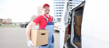 Minibüsün yanında paketleri olan gülümseyen kuryenin portresi. Paket teslimatçıda. Teslimat hizmeti ve paket alma kavramı