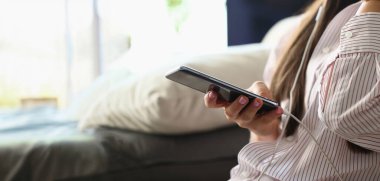 Kanepede oturan akıllı telefonlu ve müzik dinleyen bir kadının yakın çekimi. Kadın film izliyor, internette sörf yapıyor ya da mesajlaşıyor. Sosyal medya ve eğlence kavramı