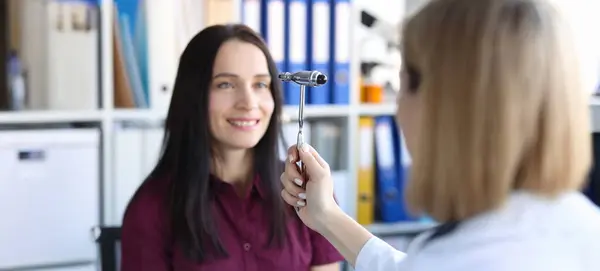 stock image Portrait of neurologist doctor driving hammer tool in front of patient eyes in clinic. Medical checkup, health diagnostics and doctor appointment concept