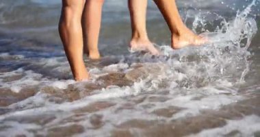 İnsanlar dinlenme tesisinde deniz dalgalarını çıplak ayakla tekmeliyor. Aktif turistler sahilde günün tadını çıkarırlar. Çiftler tatilde okyanus suyuyla oynarlar.