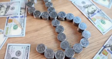 Gümüş kuruşluk madeni paralarla ve ahşap masa üst görüşüne saçılmış banknotlarla yapılmış dolar işareti. Finansal başarı kavramı. Akıllı yatırım