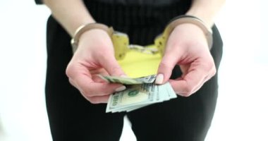 Ellerinde kelepçe olan kadın, içinde para olan zarfı ışık odasında gösteriyor. Delillerle birlikte mali suçlardan tutuklanan kişi. Rüşvet talebi için cezai tepkiler