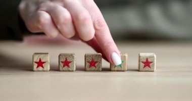 Kadının eli, kırmızı yıldızlı bloklara karşı yeşil yıldızlı tahta küp koyuyor. Liderlik kavramı ve uymama yavaş çekim