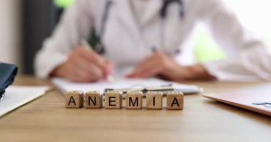 Ahşap küplere reçete yazan doktor aleyhinde Anemia yazmışlar. Klinikte harfli bloklar yavaş çekimde masada