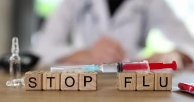 Kelimeler, şırınganın yakınındaki tahta bloklardan yapılan gribi durdurur. Masada oturan doktora karşı aşı ile. Salgın ve aşı kavramı yavaş çekim