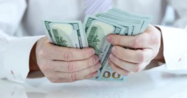 İşadamı 100 dolar nakit para sayıyor. Kârlı mali yatırım ve gelir kavramı