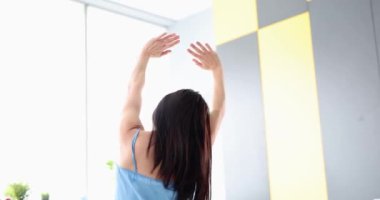 Sabah evde uyandıktan sonra kollarını açan bir kadının dikiz görüntüsü. Sabah uyanması ve olumlu duygular kavramı