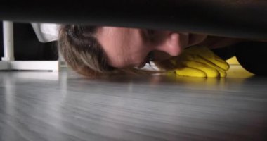 Cleaning woman in gloves takes out socks from under bed. Cleaning services concept