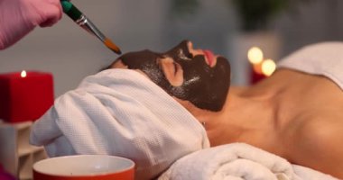 Kadın yüzüne siyah kilden maske takan bir güzellik uzmanı. Yüz maskesi konsepti gençleştirici ve nemlendirici