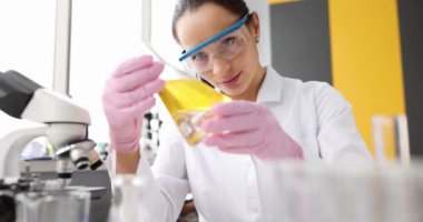 Test tüpü yağ kullanan kadın bilim adamı klinik laboratuarında araştırma yapıyor. Tıp konsepti için kimyasalın geliştirilmesi