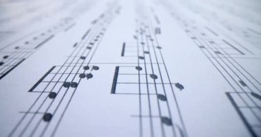 Music conceptual background macro view of white music notes with sheet music. Notes of musical work concept