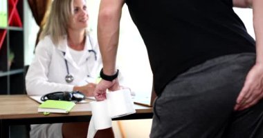 Elinde tuvalet kağıdı olan bir hasta doktor randevusunda elini rektal alanda tutuyor. 4K film yavaş çekimde. İshal kavramının önlenmesi ve tedavisi