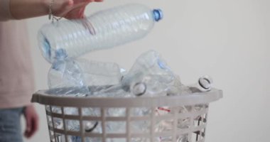 Kadın kullanılmış plastik şişeyi yavaş çekimde çöp kutusuna atıyor. Geri dönüşüm malzemeleri için atık ayıklayan bir kadın. Sürdürülebilir yaşam tarzları