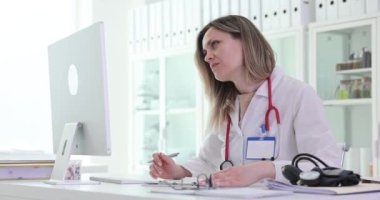 Kadın doktor bilgisayarda veri bulmak için tıbbi kayıtları dolduruyor. Terapist klinikteki iş yerinde tedavi raporu yazıyor. Sağlık hizmetleri