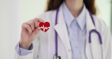 Kadın doktor kalp şeklinde broşu kalp atışı grafiğiyle süslüyor. Modern hastanedeki profesyonel kardiyolog kıyafetinin kişiliği.