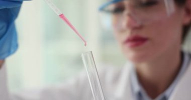 Kadın laboratuvar çalışanı tüpün içine pipetle sıvı bırakıyor. Tıbbi araştırmacı doğru deneyler için kesin ölçümler sağlar.