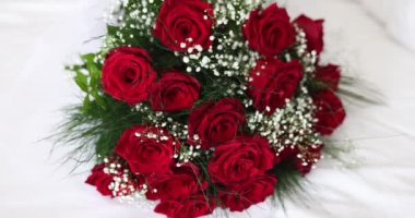 Kırmızı güllerden oluşan düğün buketi yatakta yatıyor. Güller aşkı ve tutkuyu simgeler. Yatakta buket olması odaya romantik bir hava katıyor.