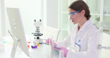 Kadın bilim adamı araştırmanın sonuçlarını titizlikle kontrol eder. Araştırmacı, tablette kaydedilen verileri bilgisayar ekranında gösterilen verilerle karşılaştırır