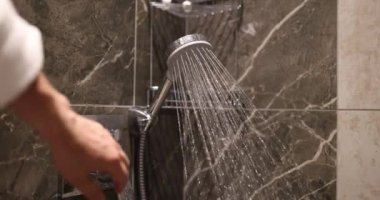 Bornozlu adam düğmeye basarken sabit su akıntısı azalmaya başlıyor. Su akışı damlaya damlaya damlaya damlaya düşer ve tamamen ağır çekim durur.