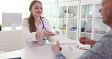 Doktor, erkek hastaya tıbbi onay formunun detaylarını açıklıyor. Hekim adama belge verir ve anlayışı doğrulamak için imza ister.