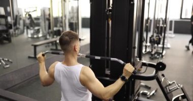 Sporcu spor salonunda kol kaslarını geliştiren egzersizler yapar. Genç sporcu, ağır çekimde modern ekipman kullanır.