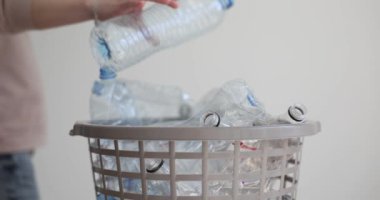 Kadın eli boş plastik şişeyi ağır çekimde çöp kutusuna atıyor. Kirliliği azaltmak için sorumluluk ve plastik sıralama kavramı