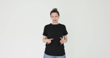 Kadın karnına dokunuyor ve gri arka planda derin bir iç çekiş veriyor. Siyah tişörtlü hoşnutsuz bayan restoranda fazla yemek yemekten rahatsız oluyor.